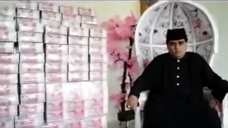 Dimas Kanjeng sitting before stacks of cash he had “conjured” out of nothing. Photo: Video screengrab