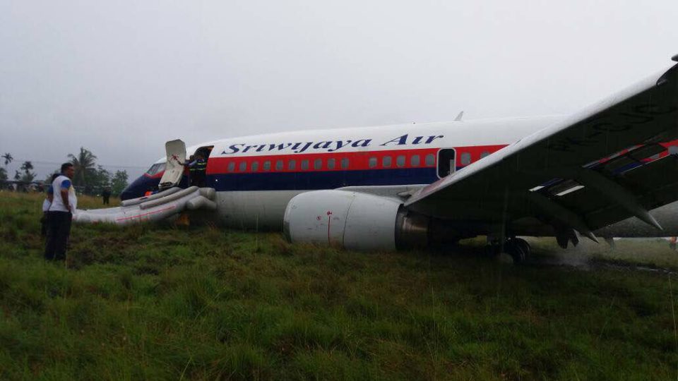 The Sriwijaya Air plane pictured resting on its belly on the grass next to the runway. Photo: Twitter
