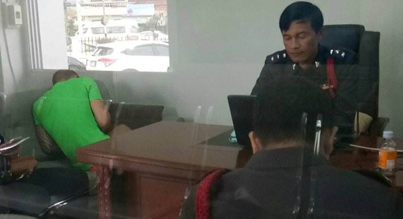 British national Danny Glass (left, in green shirt) obscures his face at Thalang Police Station Saturday.