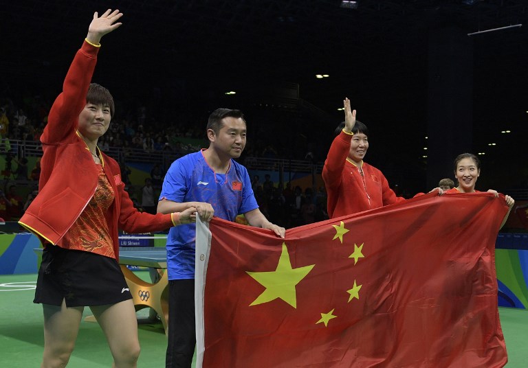 (FILES) This August 16, 2016 file photo shows (L-R) China’s Ding Ning, coach Kong Linghui, Li Xiaoxia and Liu Shiwen posing with the national Chinese flag after winning gold medals in the women’s team final table tennis at the Riocentro venue during the Rio 2016 Olympic Games in Rio de Janeiro.
One of China’s best known table tennis champions has been suspended as head coach of the national women’s team, officials said on May 30, 2017, following reports he was at the centre of a gambling debt lawsuit. AFP PHOTO / JUAN MABROMATA