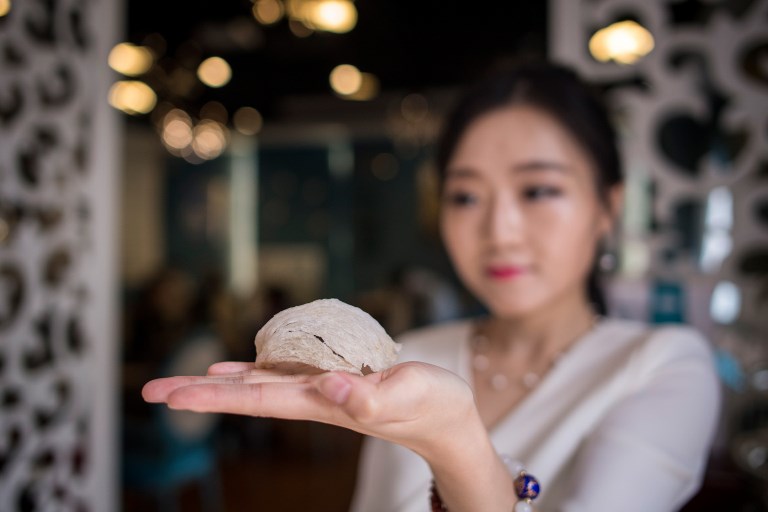 This picture taken on May 23, 2017 shows Elaine Zhang, owner of the NestCha restaurant, presenting a dried birds nest in her restaurant in Shanghai.  
The cries of amorous swiftlets echo around the dark room, an unlikely gold mine for traders in southern Myanmar who are cashing in on rising demand for the edible nests from China’s growing middle class. On the streets of Shanghai, restaurants sell birds nests as “the caviar of the East,” as it is known, for hundreds of dollars a bowl.  / AFP PHOTO / Johannes EISELE 