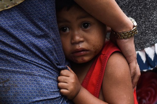 A boy clutches to his mother after residents where evacuated from their homes on the outskirts of Marawi. AFP PHOTO / TED ALJIBE
