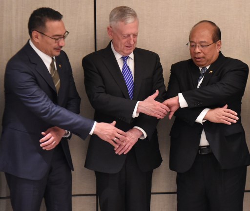 US Pentagon chief Jim Mattis (L) reaches for hand shakes with Malaysian Defence Minister Hishammuddin Tun Hussein (L) and U Thaung Tun (R), National Security Advisor of Myanmar during the 16th Institute for Strategic Studies (IISS) Shangri-La Dialogue Summit in Singapore on June 4, 2017.  
The annual Shangri-La Dialogue is attended by defence ministers from around the region and runs from June 2 to 4. / AFP PHOTO / ROSLAN RAHMAN