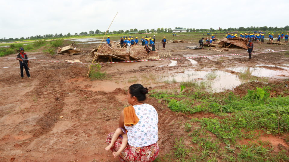 A woman holds a baby as she watches hired workers demolish the slum where she lived. Photo: Hong Sar