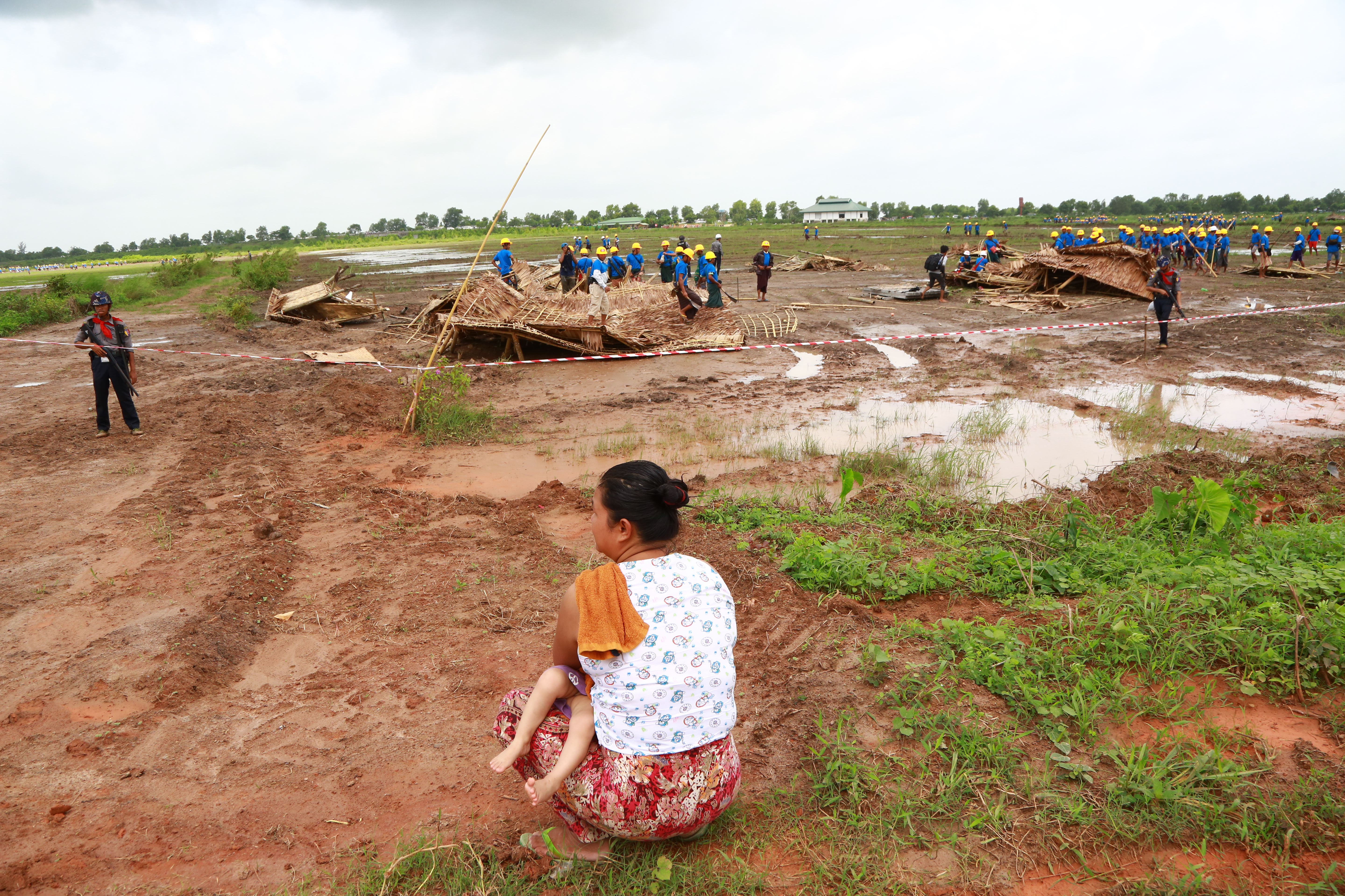 A woman holds a baby as she watches hired workers demolish the slum where she lived. Photo: Hong Sar