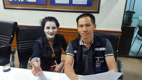 This viral photo shows murder suspect Preeyanuch Nonwangchai covering her face with white powder and smiling for a photo with a police officer.