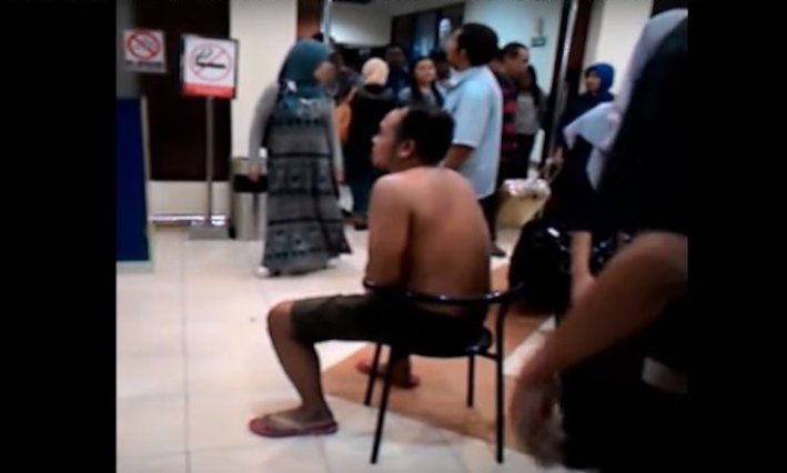 An ‘online’ taxi driver in the city of Yogyakarta, Indonesia, stripped and humiliated at the airport for violating a pick-up rule. Photo: Youtube