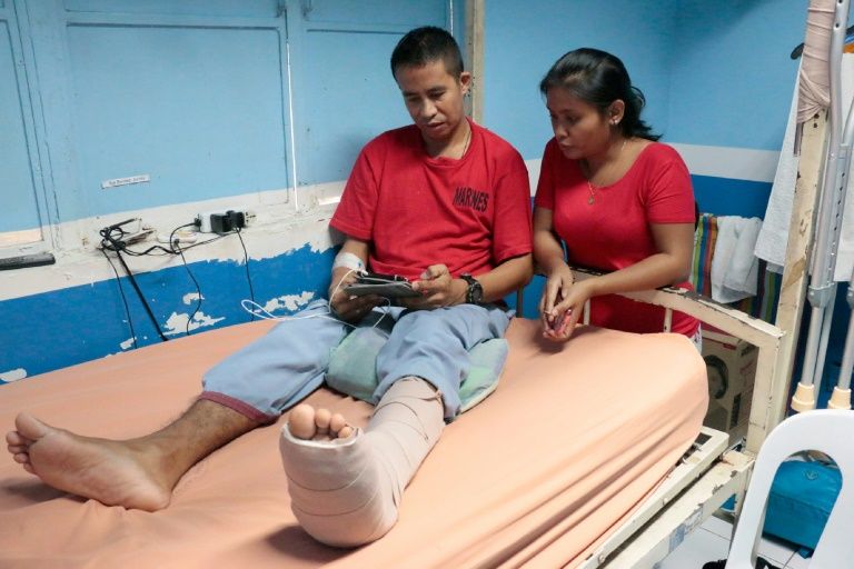This picture taken on June 20, 2017 shows Philippines Marine Sergeant Sandy Benitez (L), wounded in the ongoing conflict with Islamist militants in southern Marawi province, resting beside his wife at a military hospital in Manila. Inside the “Heroes’ Ward” at a hospital. AFP photo 