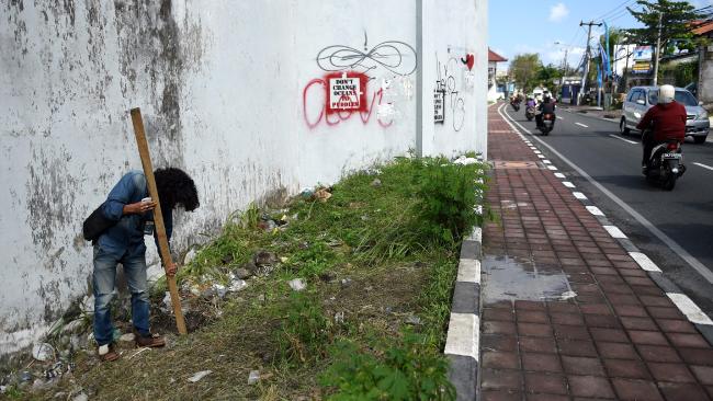 A local journalist inspects the exit hole of a tunnel dug by escapees by the perimeter wall of the Kerobokan prison in Denpasar on Indonesia’s resort island of Bali on June 19, 2017. Photo: Sonny Tumbelaka/AFP