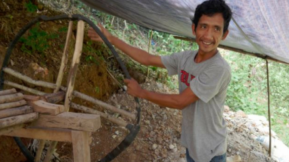 A gold miner demonstrates how he pulls up bags of ore from deep in the mine. Photo courtesy of Isabel Dunstan / UNDP Indonesia