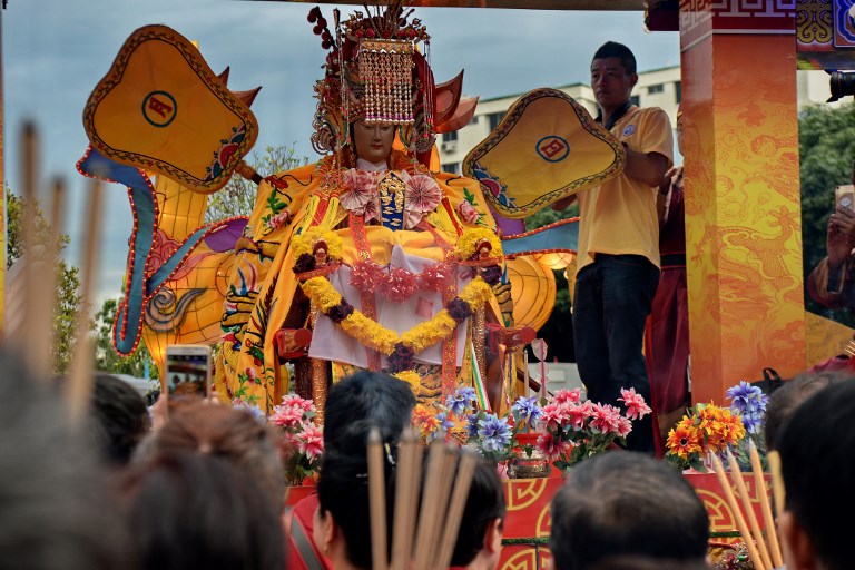Devotees make an offering with joss sticks to the idol of Chinese sea goddess Mazu during its second stop-over at a temple in Singapore on July 5, 2017. 
Photo: Roslan Rahman / AFP