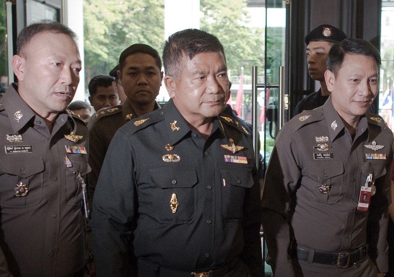 (FILES) This file photo taken on June 3, 2015 shows Thai Army Lieutenant General Manas Kongpan (C) being surrounded by police officers as he turns himself in at the police headquarters in Bangkok.
The senior Thai army general, Manas Kongpan, was found guilty of human trafficking on July 19, 2017 at a rare trial exposing the links between corrupt officialdom and the trade in people through the kingdom. / AFP PHOTO / NICOLAS ASFOURI