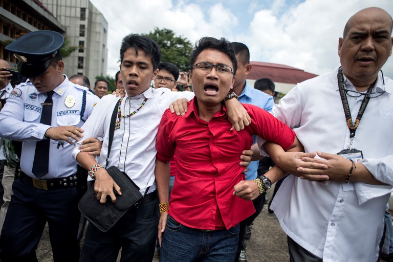Activists are escorted out form the Plenary Hall of the House of Representatives where the joint session on martial law is taking place are being escortred by security officials in Manila on July 22, 2017. 
The Philippine Congress opened a special session to vote on Duterte’s bid for an extension of martial law in the south to defeat Islamist gunmen. Duterte is widely expected to win approval for martial law in the region until the end of the year, with troops having failed to wrest back Marawi city following two months of fighting. / AFP PHOTO / NOEL CELIS