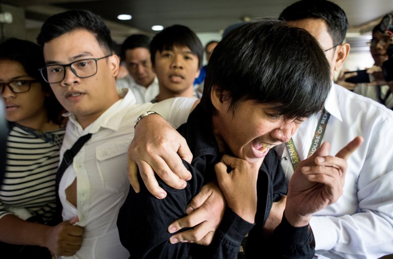 Activists are escorted out form the Plenary Hall of the House of Representatives where the joint session on martial law is taking place are being escortred by security officials in Manila on July 22, 2017. 
The Philippine Congress opened a special session to vote on Duterte’s bid for an extension of martial law in the south to defeat Islamist gunmen. Duterte is widely expected to win approval for martial law in the region until the end of the year, with troops having failed to wrest back Marawi city following two months of fighting. / AFP PHOTO / NOEL CELIS