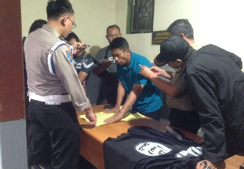 Jakarta Police officers examining an ISIS flag and a threatening note left outside a police station. Photo: Detik