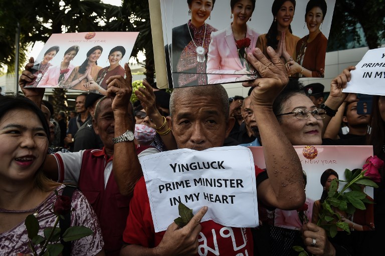 Supporters of former Thai Prime Minister Yingluck Shinawatra hold signs and images of her before she arrives at the Supreme Court in Bangkok on August 1, 2017. Photo: Lillian Suwanrumpha/ AFP