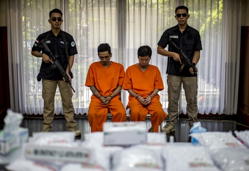 Indonesian narcotics police guard two suspects during a press conference in Jakarta on August 1, 2017, after a joint operation led by the police, national narchotics agency and customs raided a warehouse on the outskirts of Jakarta on July 21 seizing ecstasy pills.
Indonesian authorities shot dead an alleged drug trafficker and arrested two more for attempting to smuggle more than a million pills of ecstasy from the Netherlands, police said on August 2.  / AFP PHOTO / BAY ISMOYO