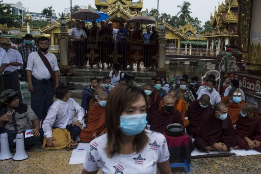 Nationalist monks sit with their alms bowls upturned while demonstrators shout anti-government slogans as the group protests near Shwedagon Pagoda. Photo: AFP / Ye Aung Thu