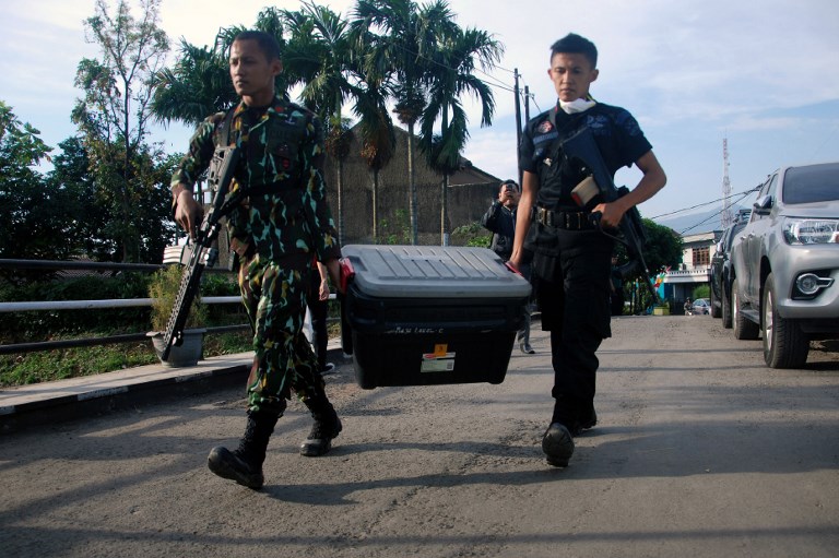 Police carry a box of evidence during a terror raid at the Jajaway village in Bandung on August 15, 2017. 
Five suspected Islamic State sympathisers have been arrested in Indonesia, a police spokesman said on August 15, adding that authorities also confiscated a chemical bomb. / AFP PHOTO / TIMUR MATAHARI