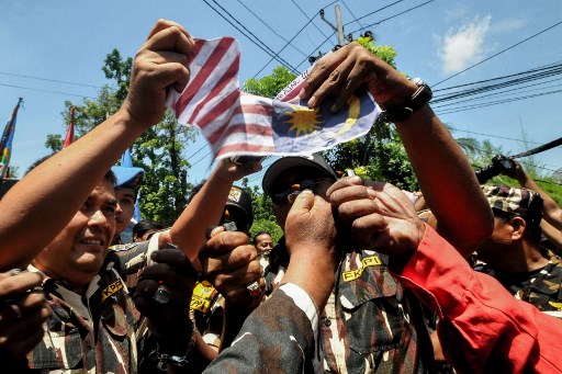 This photo taken on August 22, 2017 shows protesters tearing, burning and holding upside-down a replica of the Malaysian national flag during an anti-Malaysia rally in front of its consulate office in Medan in North Sumatra.
The Indonesian government on August 23 asked people not to overreact to a gaffe that saw Indonesia’s flag printed upside-down in a Southeast Asian Games commemorative magazine, after protests were staged in several cities. / AFP PHOTO / GATHA GINTING