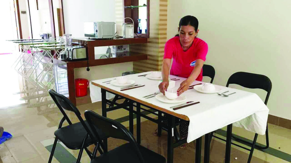 A Cambodian woman sets a table at a Phnom Penh training center on August 9, before beginning a new job in Hong Kong. Photo courtesy of the Phnom Penh Post