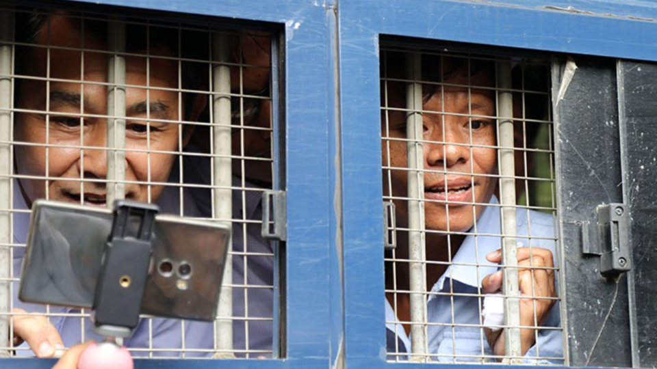 Journalists Aye Nai (L) and Lawi Weng speak to journalists from inside a prisoner transport vehicle outside the courthouse in Hsipaw in Shan State on July 28, 2017. Photo: AFP