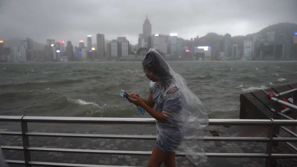 A woman wearing a plastic poncho uses her phone during the storm at Victoria Harbour on Aug 23, 2017.  ANTHONY WALLACE/AFP