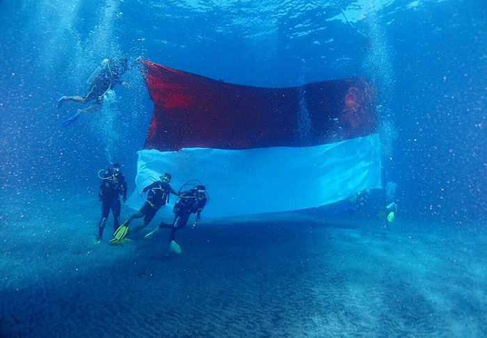 Police divers pose with a large Indonesian flag underwater at Bali’s Nusa Penida. Photo via Istimewa