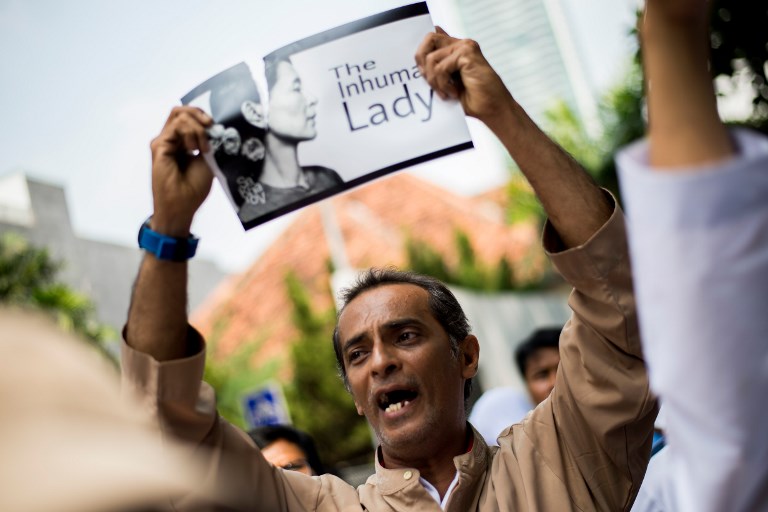 An Indonesian protester tears a picture of Myanmar’s Aung San Suu Kyi during a rally in front of the Myanmar embassy in Jakarta on September 2, 2017, to condemn Myanmar’s army and the government of Aung San Suu Kyi. / AFP PHOTO / Bay ISMOYO