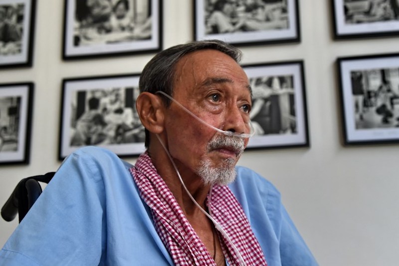 Looking frail in a wheelchair and breathing with the aid of an oxygen tank, photographer Alan Lee grasps the camera that he used to take pictures of his fellow patients at a Singapore hospice. Photo: Roslan Rahman / AFP