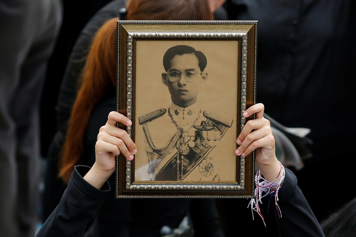A woman holds an image of King Bhumibol Adulyadej as mourners gather outside of the Grand Palace to sing for a recording of the royal anthem in honour of their king, in Bangkok, Thailand, October 22, 2016. Photo: REUTERS/Jorge Silva