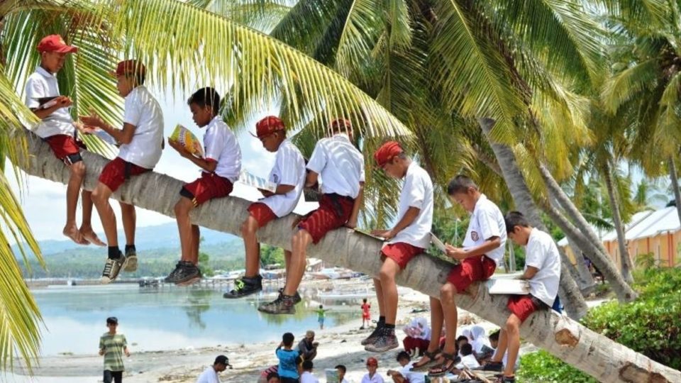 School children read books at Palipis beach in Mandar, West Sulawesi. The books were brought by library boat. Pattingalloang, which was part of a network of moving libraries called Pustaka Bergerak. Photo: Urwa/Pustaka Bergerak, CC BY-NC-SA