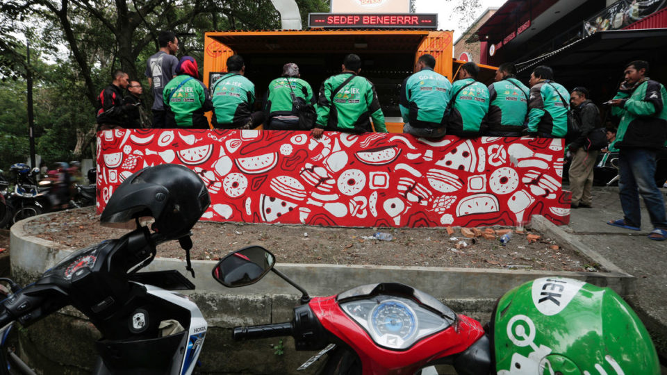 Go-Jek drivers sit as they wait for their orders at a food stall in Jakarta. File photo by REUTERS/Beawiharta
