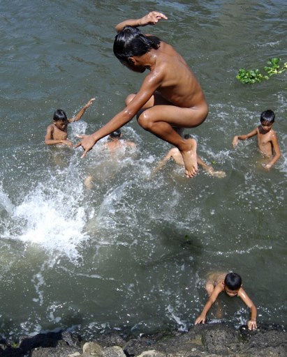 Children jump in a river in Marikina, suburban of Manila on February 27, 2010 as the Philippine enters the summer.  The Philippine Atmospheric Geophysical and Astronomical Services Administration (Pagasa), said slightly warmer than normal air temperatures would be felt in most parts of the country caused by El Nino phenomenon.    AFP PHOTO/NOEL CELIS / AFP PHOTO / NOEL CELIS