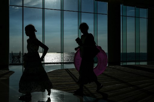 Two women are silhouetted as they walk at a hotel in Manila on August 7, 2017. / AFP PHOTO / MOHD RASFAN