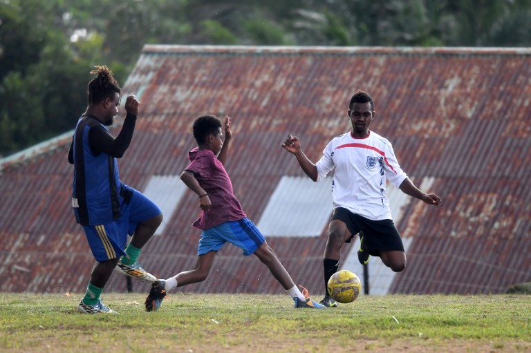 This photo taken on August 23, 2017 shows Papuan youngsters playing football on a field in Sorong in Indonesia’s Papua. 
Boaz Solossa, Indonesia’s football captain, is known for his quick turn of pace and sharp instincts — as well as his eye for goal. But he’s not alone: Solossa is just one of many outstanding players born and bred in the far-flung, rebellious province of Papua, which has become known as a breeding ground for athletic talent. / AFP PHOTO / GOH Chai Hin