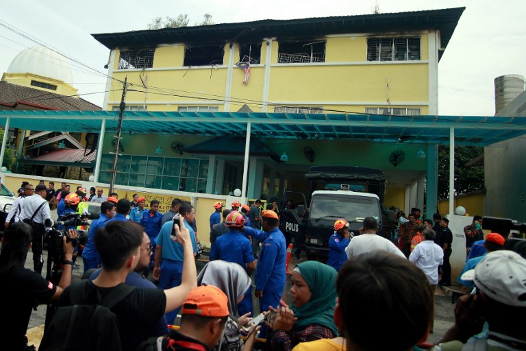 (FILES) This file photo taken on September 14, 2017 shows Malaysian Fire and Rescue personnel standing outside the Darul Quran Ittifaqiyah religious school in Kuala Lumpur.
Two Malaysian teenagers were charged with murder on September 28, 2017 in connection with an intentional fire that killed 23 children and teachers at an Islamic school this month.
The two, who cannot be named because they are below 18 years of age, were also slapped with drug abuse charges along with four others, while a seventh suspect was released for lack of evidence, state prosecutors said.
 / AFP PHOTO / SADIQ ASYRAF