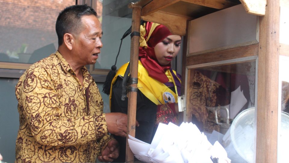 Siti Marfuah valedictorian of her graduating class at Magelang’s Universitas Tidar, helping her father serve sate at her graduation. Photo: Universitas Tidar 