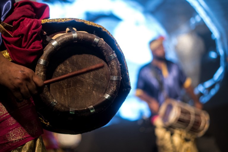 This photograph taken on November 5, 2017 shows Malaysian musicians of Indian ethnicity beating “urumee” drums during a performance in Bukit Sentosa, around 50 kms outside Kuala Lumpur.
Malaysian Indian musicians bang drums on a stage shrouded in smoke, singing in Tamil, as dancers wearing shimmering gold outfits adorned with peacock feathers gyrate to the pounding rhythm. The “urumee melam” ensemble are performing a traditional form of folk music brought to Malaysia generations ago by Indian labourers but which is now enjoying a revival among the country’s South Asian community. / AFP PHOTO / Manan VATSYAYANA / TO GO WITH Malaysia-India-music-culture, FEATURE by Patrick Lee