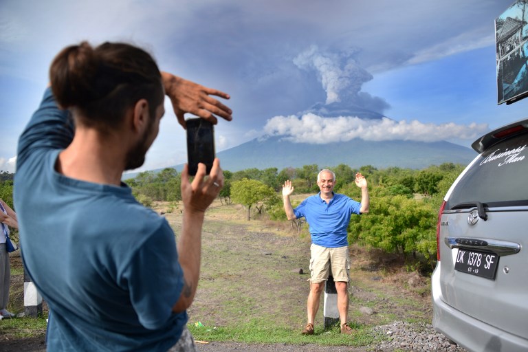 A foreign tourist takes pictures in front of Mount Agung erupting seen from Kubu sub-district in Karangasem Regency, on Indonesia’s resort island of Bali on November 27, 2017. Photo: Sonny Tumbelaka/AFP