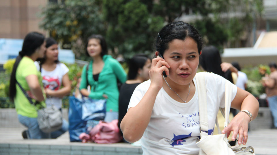 A domestic worker in Hong Kong calls homes. Photo: Flickr / KC Wong