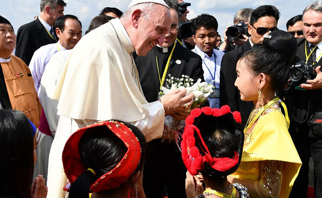 Pope Francis is greeted by children in traditional clothing upon his arrival at Yangon International Airport on November 27, 2017. / Vincenzo PINTO / AFP/