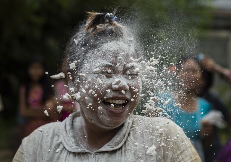 A woman reacts with flour over her face while playing a game with cake-making ingredients as part of local festivities marking Myanmar’s 70th Independence Day in Yangon on Jan. 4, 2018. / AFP PHOTO / YE AUNG THU