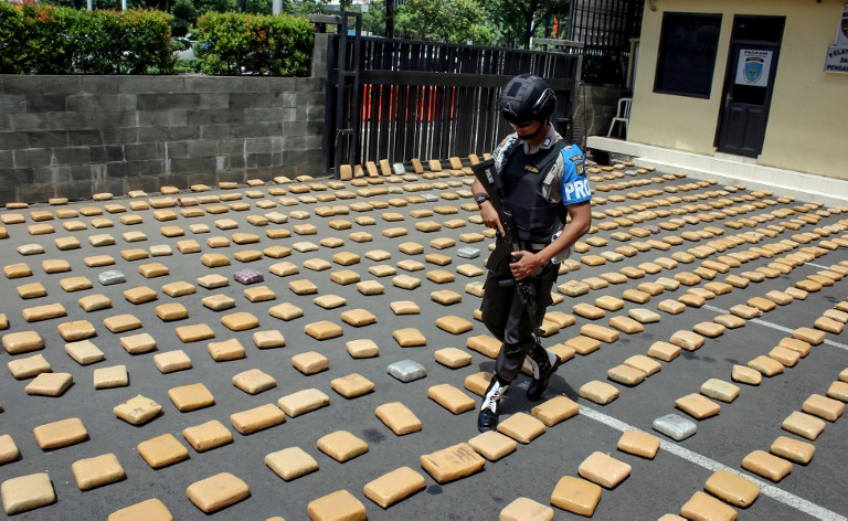 An Indonesian policeman walks amongst bricks of tightly-wrapped cannabis during a press conference in Jakarta on January 4, 2018.
Indonesian authorities have seized 1.3 tonnes of marijuana and arrested six people in a major drug bust on New Year’s Eve, police said on January 4. / AFP PHOTO / MAMAN