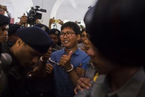 Reuters journalist Wa Lone (C) is escorted by police as he arrives for a court appearance in Yangon on January 10, 2018. / AFP PHOTO / YE AUNG THU