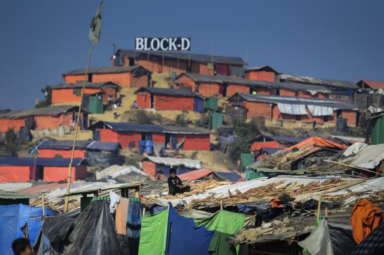 A Rohingya refugee child sits with drying wood for cooking on his roof at Thankhali refugee camp in Bangladesh’s Ukhia district on January 22, 2018. / AFP PHOTO / Munir UZ ZAMAN