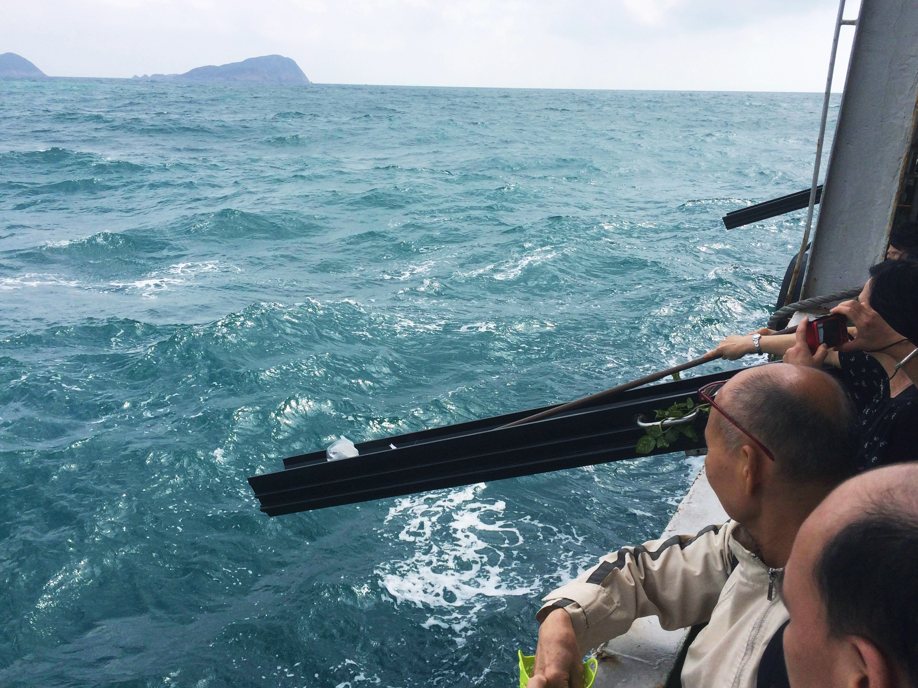 Cremated ashes, held in a dissolvable bag, are pushed into the sea down a chute decorated with plastic leaves and flowers. A woman uses a stick to dislodge a bag of ashes after it gets stuck. Picture: Mandy Zheng