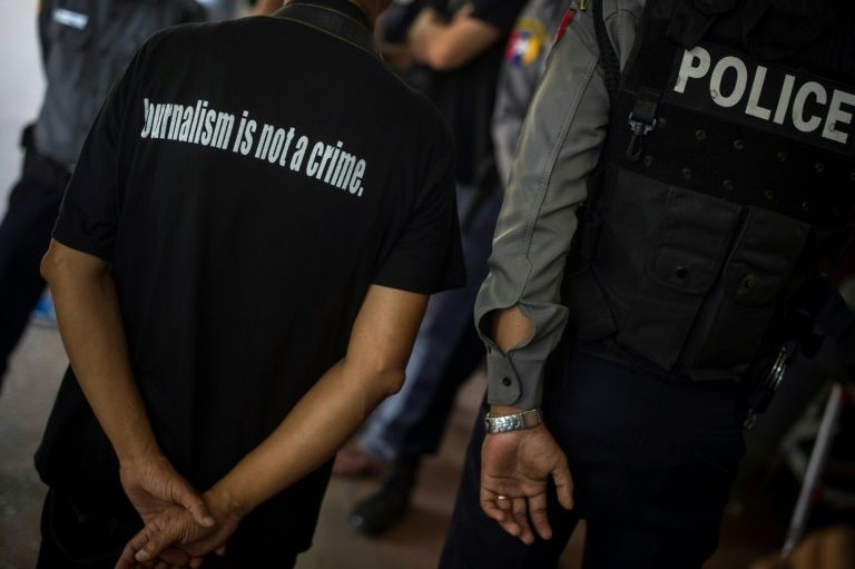 A local journalist (L) stands next to a police officer as Reuters journalists Kyaw Soe Oo and Wa Lone appear in court in Yangon on Jan. 10, 2018. / YE AUNG THU / AFP /