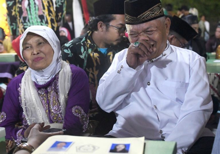 Muhammad Nasir (R), 64, and his wife Aminah (L), 65, join 436 other couples in a free mass wedding in Jakarta on December 31, 2017, despite being married since 1968 due to financial reasons and Islamic laws. AFP PHOTO/Goh Chai Hin