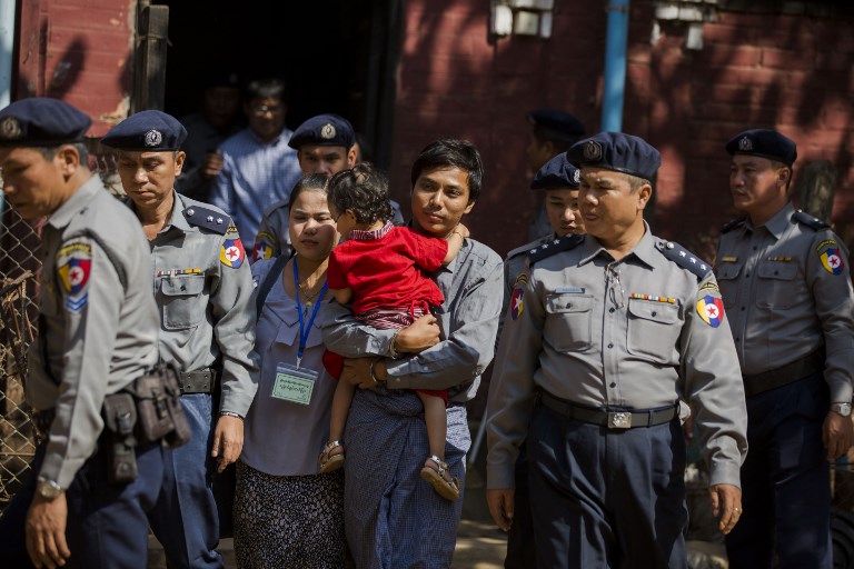 Reuters journalist Kyaw Soe Oo (C) carries his daughter while walking in handcuffs after a bail hearing at a courthouse in Yangon on February 1, 2018. / AFP PHOTO / Aung Kyaw HTET